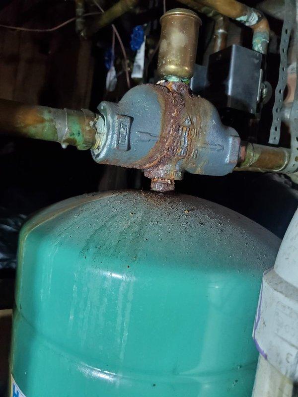 Responded to service call for a water boiler exhibiting vibration issues in residential basement. Inspection revealed severe corrosion and deterioration on multiple copper pipe junctions and valves, particularly at the pressure regulator mounted on the expansion tank. Replaced corroded components, secured loose fittings, and performed system test to confirm proper operation with no further vibration.