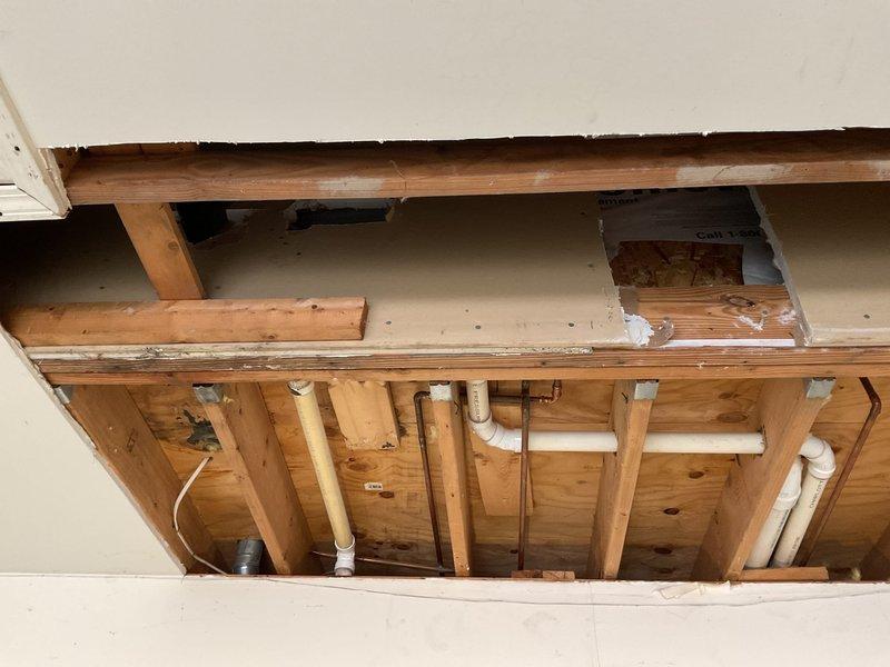 Responded to a water leak in customer's garage. Removed drywall to access the plumbing system, revealing leaking PVC and copper pipes running through wooden wall framing. Repaired damaged pipe sections and connections, ensuring proper sealing and function of the residential water supply system.