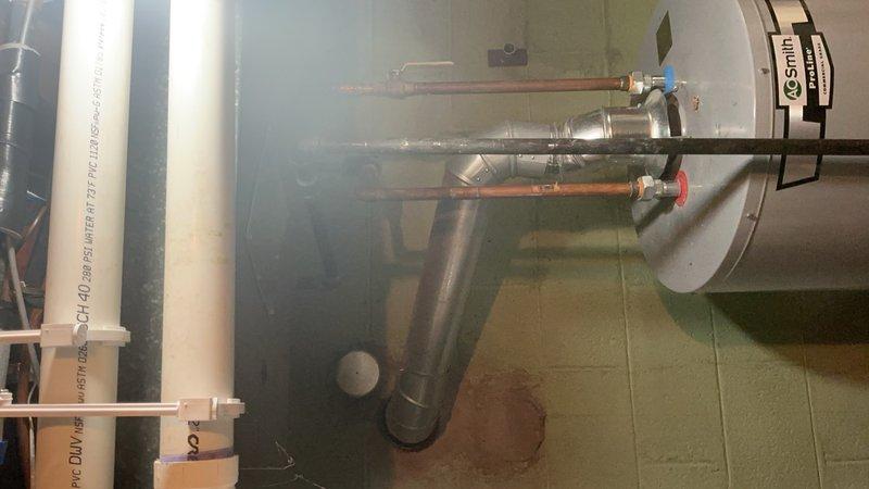 Completed installation of a new water heater in utility area, including proper connection of copper supply lines with hot/cold valves and PVC drainage piping. System was properly vented with appropriate ductwork and all connections were secured and tested for proper operation.