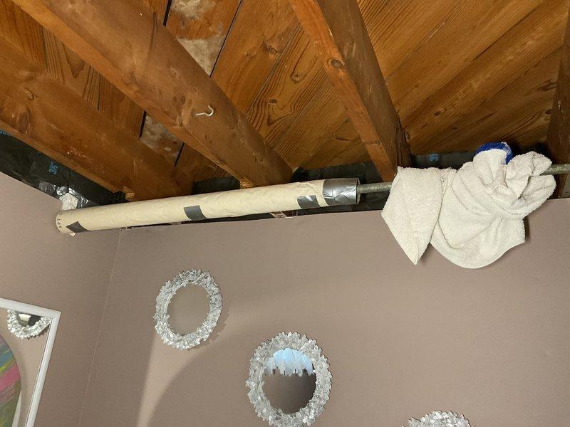 Replaced corroded shower handle, shower head, and drain trap in bathroom with purple walls. Accessed plumbing through wall panel, revealing significant water damage and corrosion on copper supply lines. Completed installation of new components and verified proper function with no leaks.