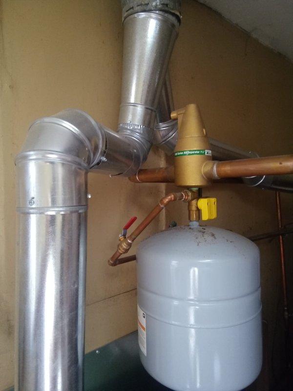 Responded to water leak service call for pipe connected to hot water tank/boiler system. Inspection revealed significant water damage around ceiling duct penetration point, with visible staining and deterioration spreading from the pipe entry. Repaired leak in the metallic ductwork and associated copper pipe connections to prevent further damage to the utility area ceiling.