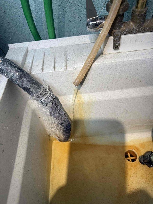 Responded to water leak complaint for 20-year-old furnace located in basement. Diagnosed issue as condensate drainage problem with significant mineral buildup in utility sink drain. Repaired leaking connection at copper pipe junction by replacing clamp fitting and securing all plumbing components to prevent future leakage.