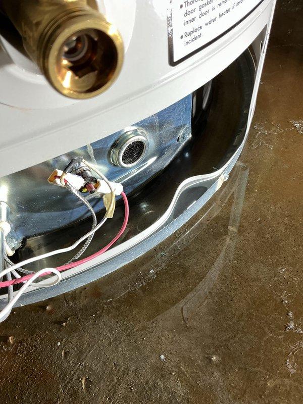 Conducted diagnostic inspection of a leaking 50-gallon hot water tank in basement that was previously replaced under warranty in December 2022. Accessed internal components to evaluate failure point, documenting evidence of water leakage at base of unit. Identified this as second warranty claim on system originally installed in 2017, with current warranty valid until June 2027. Photos documented exposed heating chamber and valve assembly for warranty claim documentation.