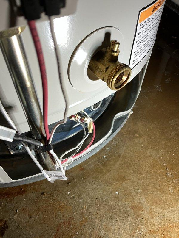 Conducted diagnostic inspection of a leaking 50-gallon hot water tank in basement that was previously replaced under warranty in December 2022. Accessed internal components to evaluate failure point, documenting evidence of water leakage at base of unit. Identified this as second warranty claim on system originally installed in 2017, with current warranty valid until June 2027. Photos documented exposed heating chamber and valve assembly for warranty claim documentation.