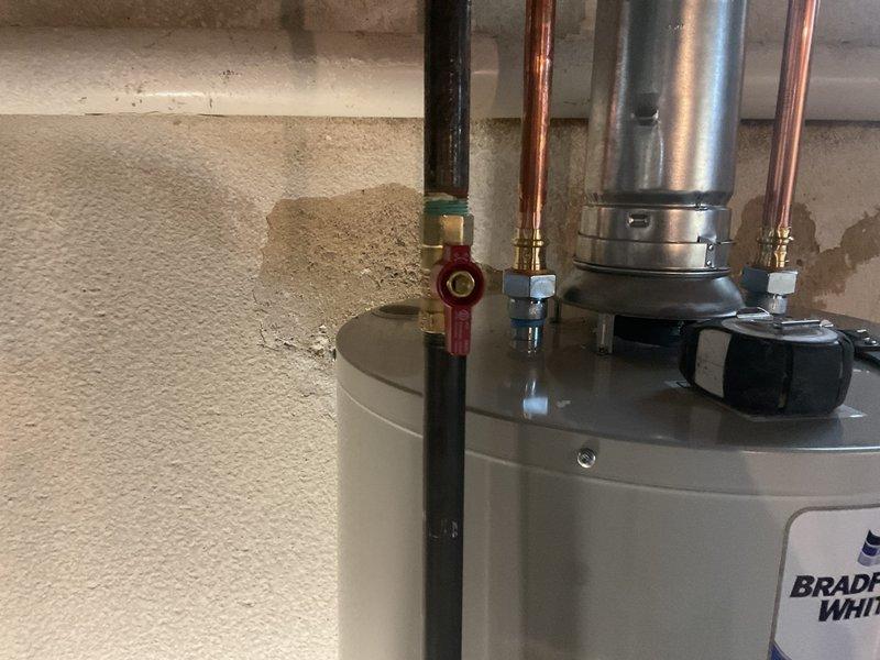 Successfully installed a 40-gallon Bradford White water heater in basement utility area, complete with all necessary copper and black pipe connections. Installed proper venting with silver flue pipe and verified all fittings were secure with no leaks. Connected existing plumbing system with appropriate soldered joints between copper and galvanized sections.