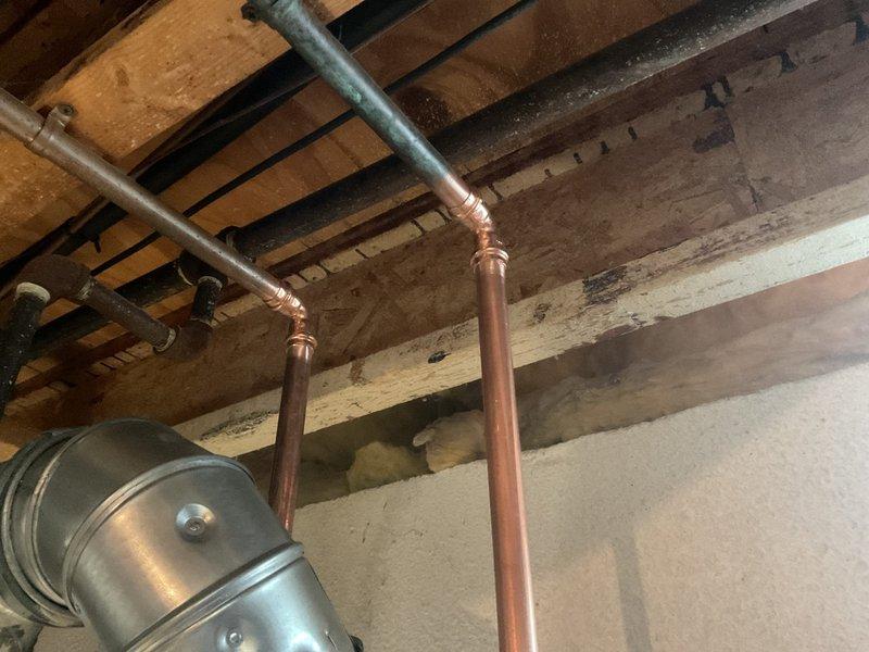 Successfully installed a 40-gallon Bradford White water heater in basement utility area, complete with all necessary copper and black pipe connections. Installed proper venting with silver flue pipe and verified all fittings were secure with no leaks. Connected existing plumbing system with appropriate soldered joints between copper and galvanized sections.