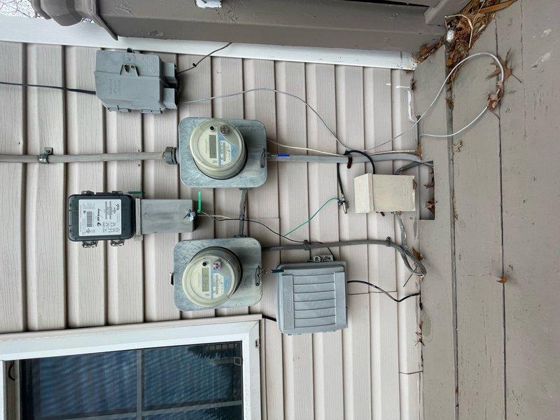 Performed comprehensive inspection of exterior electrical service equipment including meters, conduit systems, and junction boxes. Identified deteriorating wall surface with peeling paint around service entrance panel and Y-branch conduit installation. Documented condition of utility meters and associated wiring connections for future reference.