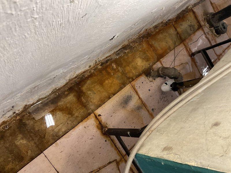 Responded to service call for clogged drain pipe in basement of 40-year-old residential property. Diagnosed severely deteriorated waste pipes connected to washtub showing significant rotting and water damage with visible mold growth along concrete wall junction. Conducted additional assessment of customer's water heater that had failed city inspection requirements per customer request.