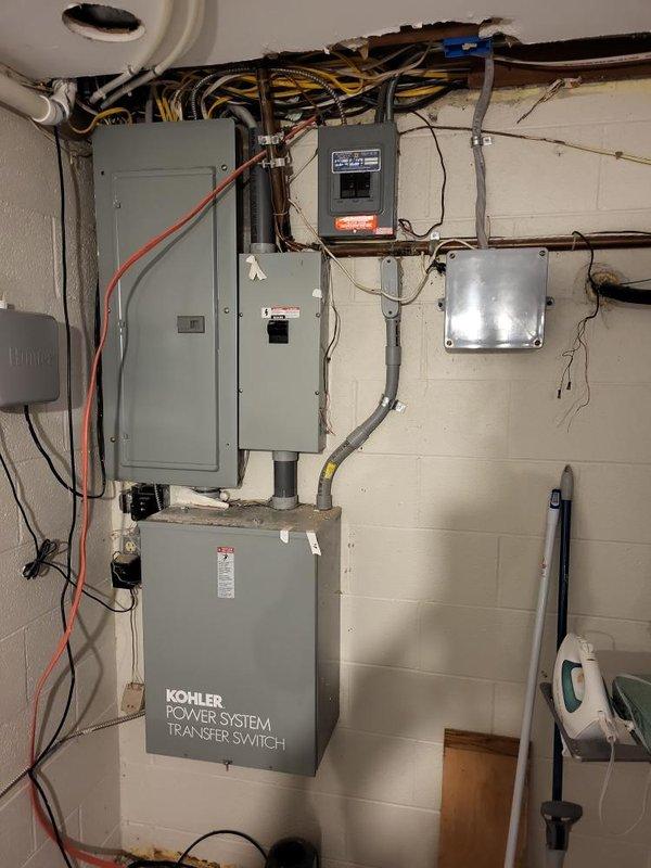 Performed evaluation for replacement of existing whole home generator system. Inspected current Kohler Power System Transfer Switch installation and associated electrical panels mounted on concrete block wall. Assessed exterior conduit routing and connection points between generator location and main electrical system. Documented current configuration for proper replacement specifications and sizing requirements.