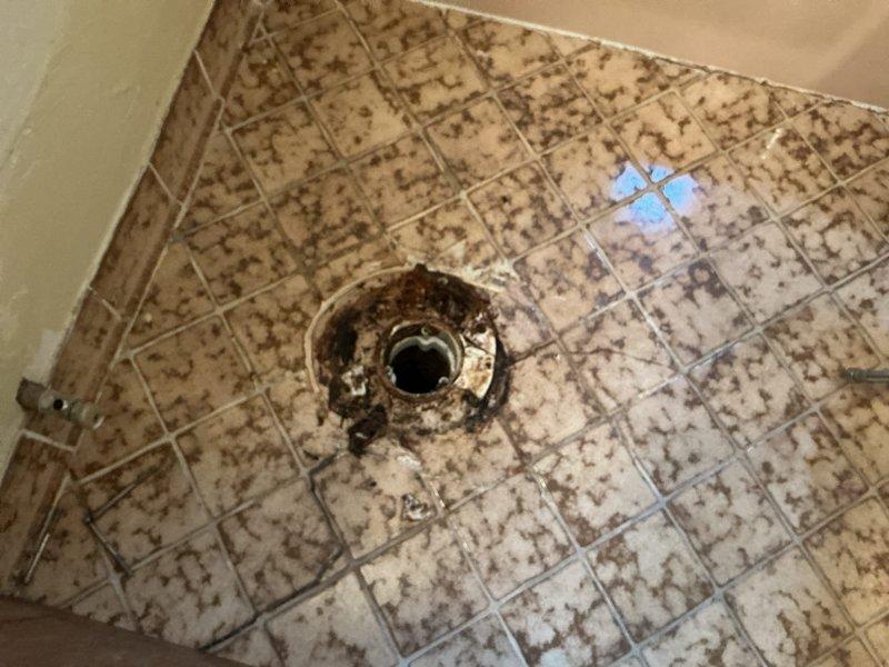 Responded to service call regarding a wobbly toilet in upstairs bathroom. Upon inspection, identified deteriorated toilet flange as the source of instability. Documented condition of bathroom fixtures and surrounding floor area, noting significant corrosion and buildup around a separate floor drain that may require future attention. Diagnostic completed; awaiting landlord approval for repair work.