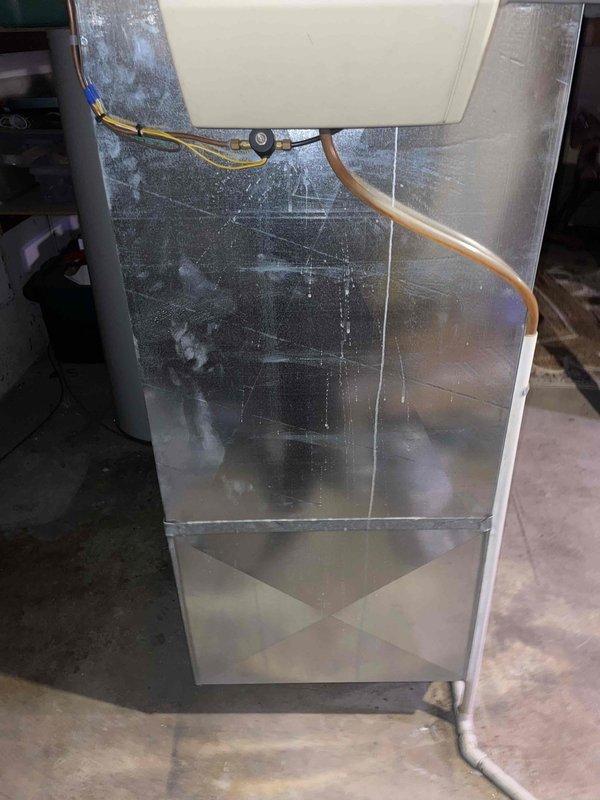 Performed assessment of 10+ year old natural gas furnace located in basement. Unit is operational but showing significant wear with visible scratches on metal cabinet, requiring replacement. Observed existing ductwork with repair patches and metal tape sealing in adjacent area, which will need to be properly connected to new furnace system when installed.