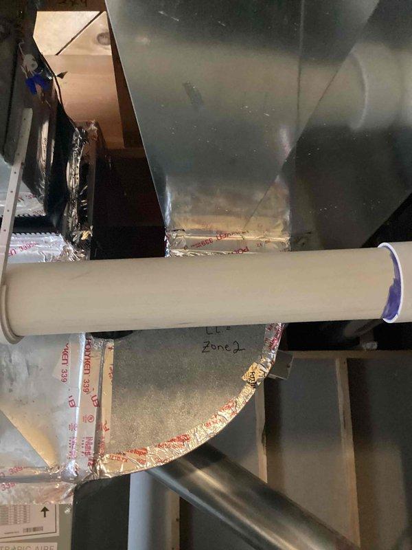 Conducted furnace replacement estimate for 12-year-old unit located in basement. Inspected existing HVAC system including ductwork connections, PVC ventilation piping, and zone control components. Documented current installation with particular attention to the sealed joints in galvanized metal ductwork and insulated components for proper assessment of replacement requirements.