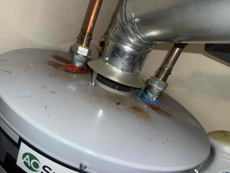 Responded to service call for reported furnace leak occurring since hot water tank installation. Diagnostic inspection revealed significant rust and corrosion at copper pipe connections on the 20+ year old furnace, with visible water staining on tank surfaces and connection points. Determined water heater flue connections were improperly sealed, causing condensation to accumulate and leak onto furnace components.