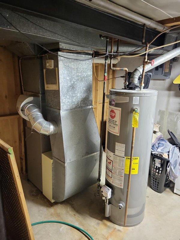 Conducted a comprehensive assessment of the aging heating system located in the basement, documenting the current installation which includes a furnace unit with connected PVC ventilation pipes, metal ductwork, and integrated Space-Gard air filtration system. Prepared replacement quote for complete HVAC system upgrade, noting proximity to water heater and existing utility infrastructure that will need to be considered during installation.