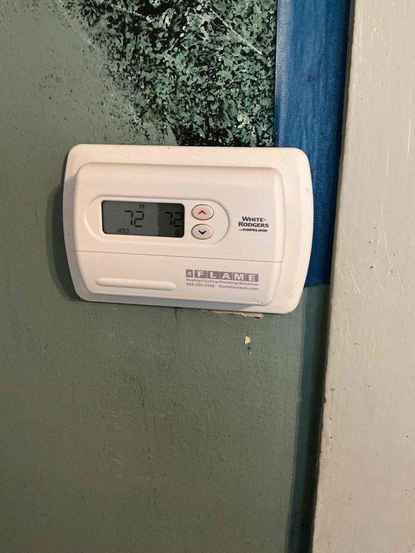 Responded to service call for non-functioning White-Rodgers thermostat that failed to maintain settings. Diagnosed issue with 3-year-old unit mounted on wall adjacent to main level utility room furnace. Observed evidence of moisture/mold growth on surrounding wall which may have contributed to operational failure; recommended remediation of wall condition to prevent future thermostat malfunctions.
