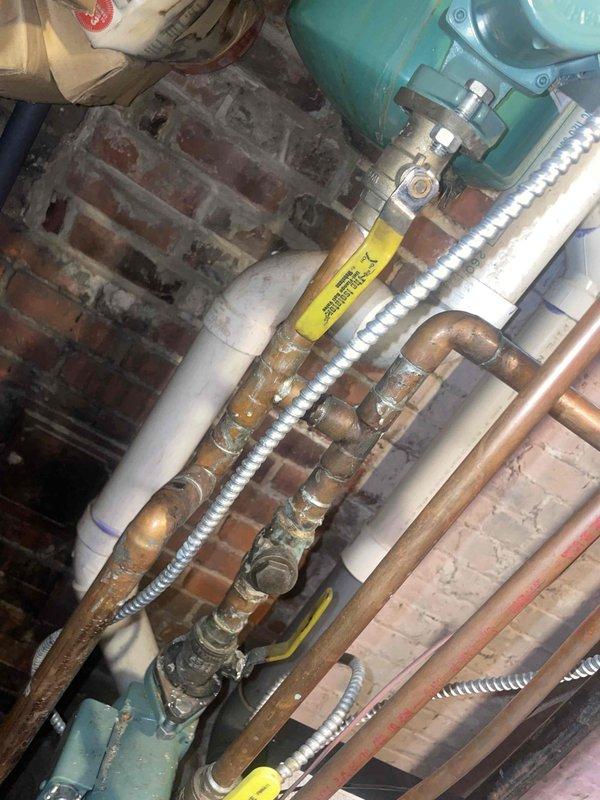 Conducted assessment of aging hot water boiler system in residential basement showing multiple pipe leaks at joints and improper exhaust configuration (mixed PVC and metal components). Documented significant concerns including vibration during operation, signs of water damage on surrounding brick walls, and visible corrosion on copper piping components. Estimate provided for necessary repairs to seal leaking connections and standardize exhaust system to prevent potential safety hazards.