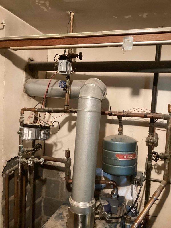 Responded to service call for a leaking boiler over 10 years old located in the basement. Upon inspection, identified water staining on the ceiling near the exhaust flue, indicating ongoing leakage from the aging system. Performed diagnostic assessment of the complete heating system including the boiler unit, expansion tank, and associated copper piping network to determine the source of the leak.