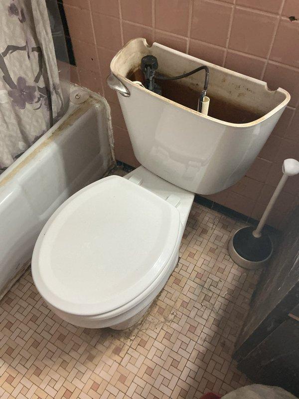 Inspected bathroom toilet with significant internal tank deterioration and mineral buildup, requiring flush valve replacement and thorough cleaning of components. Also addressed severely corroded floor drain with extensive surrounding water damage, replacing the drain assembly and sealing to prevent further deterioration of the tile flooring.