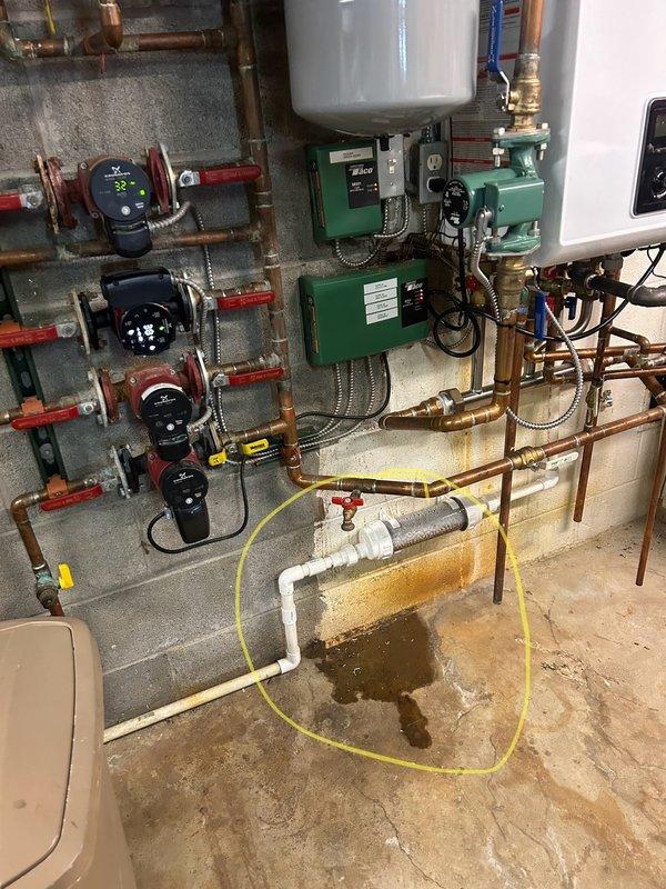 Responded to water leak issue with Navien combi unit. Identified active leak at PVC pipe connection in mechanical room, with standing water and staining visible on concrete floor. Diagnosed and repaired faulty connection in the condensate drainage system where moisture was visibly accumulating.