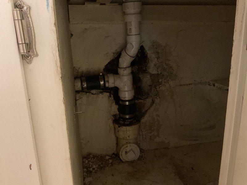 Performed main drain cleanout requiring K1500 heavy-duty equipment due to severe blockage. Inspection revealed significant water damage and mold growth around pipe connections in the utility cabinet, with deterioration of surrounding wall materials. The PVC P-trap configuration showed deterioration at joints, indicating ongoing moisture issues that were addressed during service.