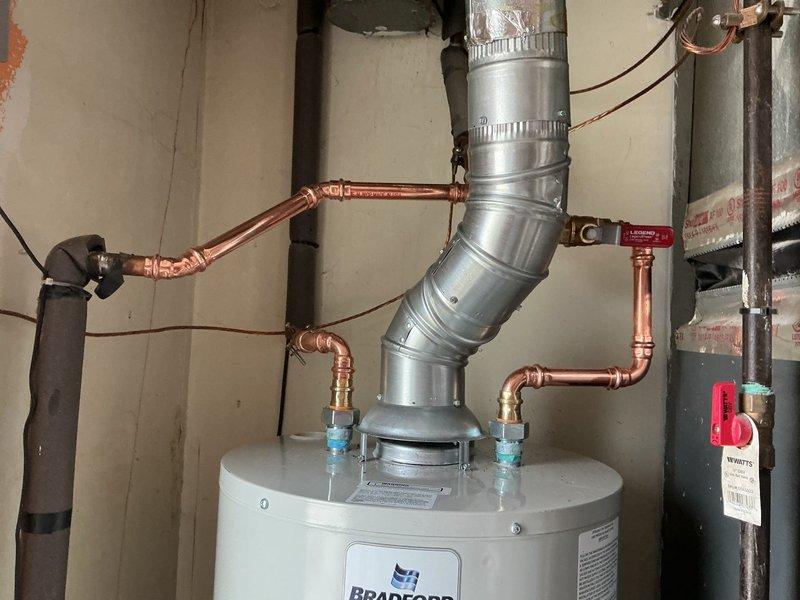 # Plumbing Install - Tanked Water Heater

## Job Description

Completed installation of a Bradford White tanked water heater unit in basement utility area. Installed new water heater with proper venting system, including segmented metallic vent pipe secured with metal clamps and routed at appropriate angle for safe exhaust. Connected copper supply lines to unit with dielectric unions at connection points to prevent galvanic corrosion. Installed shut-off valve with accessible handle for service and emergency shutoff capability. Verified all plumbing connections for proper fit and leak-free operation. System tested and confirmed operational upon completion of installation.