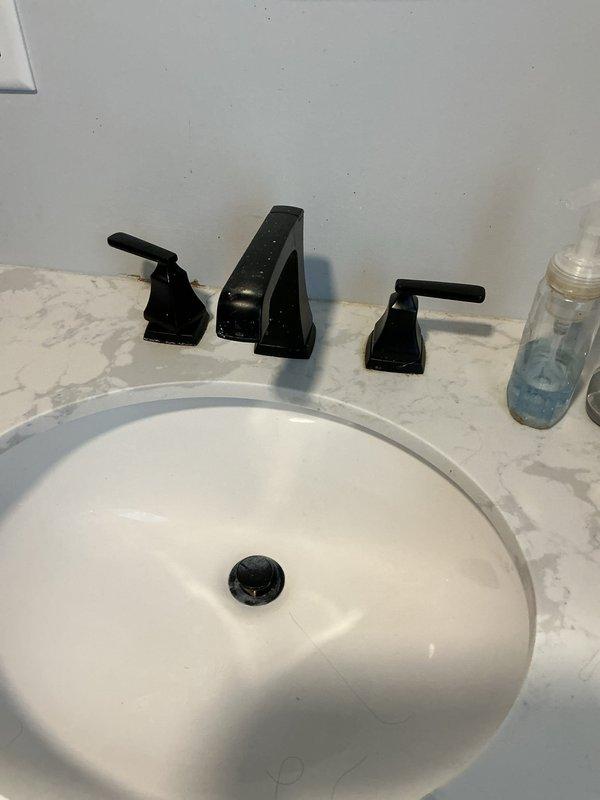 # Plumbing Service Report - Faucet Repair

Responded to service call for loose Delta faucet handle on hot water side. Upon inspection, found the hot water handle mounting hardware had become loose at the deck plate connection, causing significant movement in the fixture while maintaining water-tight integrity with no active leaks present. Disassembled the three-hole widespread faucet configuration, exposing the valve cartridge and mounting assembly. Tightened the mounting hardware and valve connections to manufacturer specifications, secured the deck plate escutcheon, and reassembled all components. Tested both hot and cold water handles for proper operation and confirmed stable mounting with no movement or play in the fixtures.