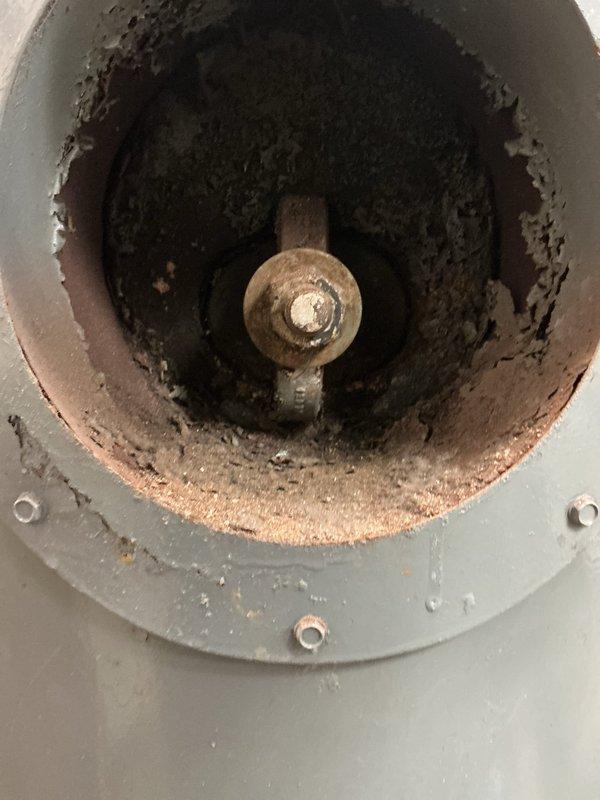 Performed CSD1 inspection and comprehensive cleaning on single commercial boiler unit located inside shop. Upon arrival, found significant soot and combustion byproduct accumulation within combustion chamber and flue passages, indicating extended operation without maintenance. Access panel and exterior surfaces exhibited heavy rust staining, corrosion, and paint deterioration consistent with moisture exposure and aging equipment.

Conducted thorough internal cleaning of combustion chamber, removing heavy carbon deposits and debris from chamber walls and surfaces. Cleaned and inspected burner assembly, flue passages, and heat exchanger sections. Evaluated hex nut and bolt assemblies showing signs of corrosion and tarnishing. Assessed structural integrity of tank base and circular access panel, noting advanced rust penetration and pitting in multiple areas. Documented extensive corrosion patterns on access cover plate and surrounding metal surfaces with rust bleeding through painted exte