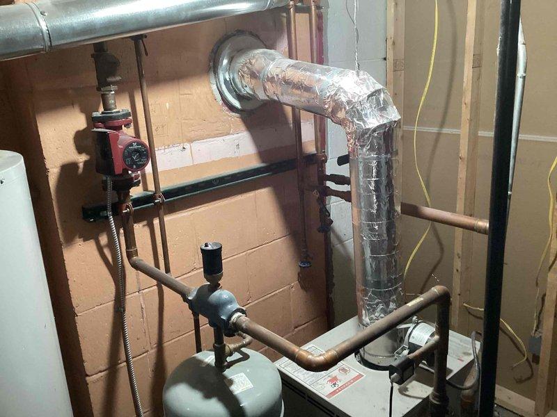 Responded to service call for leaking automatic air vent on residential boiler system approximately 10-15 years old. Upon arrival, inspected boiler and associated components in basement mechanical room. Confirmed active leak at automatic air vent assembly. Assessed condition of existing copper piping, expansion tank, circulator pump, and exhaust venting system. Removed failed automatic air vent from boiler piping. Installed replacement automatic air vent with proper thread sealant and torque specifications. Verified proper operation of new air vent and checked for leaks. Tested boiler system operation and confirmed all components functioning correctly with no active leaks present upon departure.