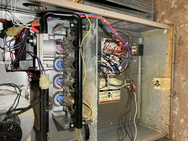 Responded to service call for 10+ year old furnace in basement blowing cold air. Performed diagnostic inspection of gas furnace and air handler unit, examining internal components including heating elements, control board, electrical connections, and gas valve assembly. Identified issue with heating system operation, inspected all wiring connections (multiple circuit wires including red, orange, purple, yellow, black, and white leads), verified gas supply connections, and assessed overall equipment condition showing age-related wear and dust accumulation.