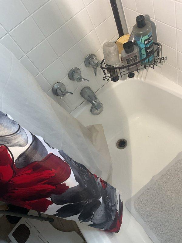 Responded to service call for leaking shower valve in residential bathroom. Upon arrival, inspected four-handle shower/tub valve assembly mounted on white tiled wall. Accessed plumbing system through wall cavity to diagnose source of leak. Inspection revealed aging valve components and corroded pipe fittings within wall structure. Exposed plumbing infrastructure showed signs of wear consistent with leak symptoms reported by homeowner. Documented existing conditions via photography for service records. Assessed valve assembly and determined repair requirements for proper resolution of leaking condition.