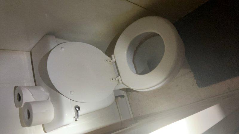 Responded to service call for excessively running toilet in main level bathroom off garage in approximately 40-year-old home. Upon arrival, assessed existing toilet and confirmed constant running condition due to worn internal components. Per customer request, proceeded with complete toilet replacement rather than repair of aging fixture. 

Shut off water supply at existing valve and disconnected water supply line from tank. Removed toilet mounting bolts and lifted old toilet from floor flange. Scraped old wax ring residue from floor flange and inspected flange condition for proper seal compatibility. Cleaned mounting area thoroughly to ensure proper installation surface.

Installed new wax ring onto floor flange and carefully positioned new white ceramic toilet onto flange, aligning mounting holes. Secured toilet to floor with new brass closet bolts and washers, torquing evenly to prevent rocking while avoiding over-tightening that could crack porcelain base. Verified toilet was level