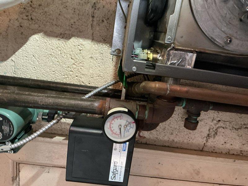 Responded to callback for no heat condition on boiler system in apartment above garage. Customer reported thermostat set to 65°F with no heat output, requiring use of space heaters. Upon inspection, identified multiple failed components requiring replacement: control board, pressure relief valve, air vent, and expansion tank. Documented system conditions with photos showing aged copper piping, pressure gauge assembly, blower motor housing, capacitor, and digital control unit with associated wiring. Ordered necessary parts including expansion tank for pickup and arranged for control board, pressure relief valve, and air vent delivery to shop for installation upon arrival.