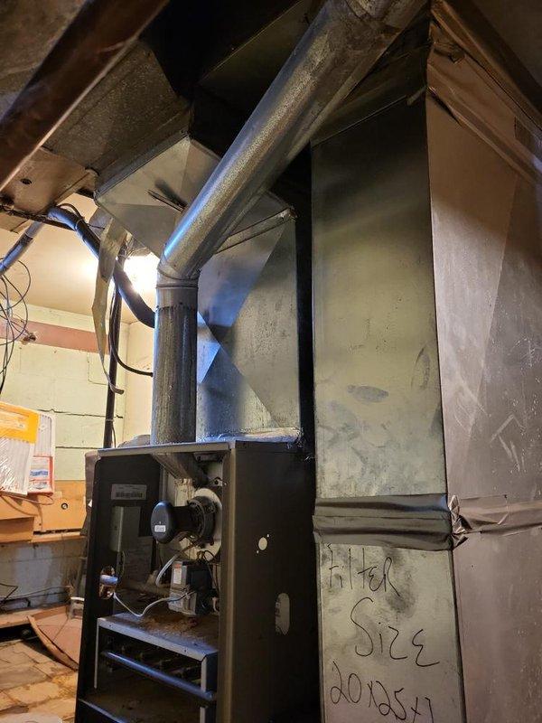 Conducted comprehensive assessment of 20-year-old residential HVAC system located in basement for equipment replacement estimate. Evaluated existing furnace unit with white metal cabinet, associated PVC condensate piping, flexible conduit connections, and exhaust flue system. Inspected air conditioning system components and existing ductwork configuration, noting 20x54 supply trunk dimensions. Documented current equipment conditions, installation layout, and mechanical room environment through photographic survey. Provided detailed replacement options and recommendations for complete heating and cooling system upgrade to improve efficiency and reliability.