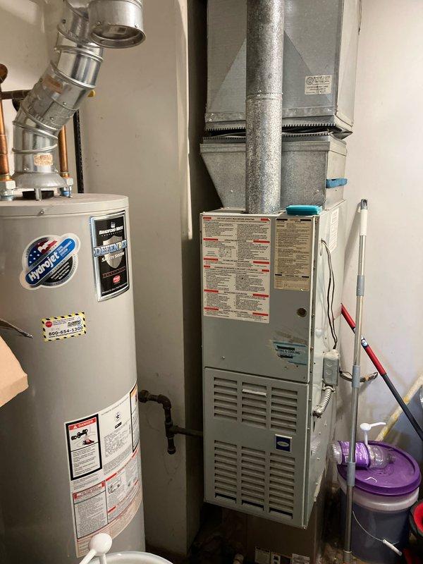 Completed diagnostic evaluation on 1996 furnace system located in condo unit near kitchen area presenting with humming noise complaint. Upon inspection, identified multiple critical failures including blower motor exhibiting rattling and grinding sounds with active oil leakage, inducer motor displaying faint rattling during startup cycle, and cracked heat exchanger with popped eyelet and visible fracture initiation. Noted heat exchanger had previous replacement performed in 2009. System accompanied by 2008 air conditioning unit. Provided comprehensive replacement estimate for furnace system due to severity of heat exchanger compromise and motor deterioration representing safety concern and end-of-life equipment condition.