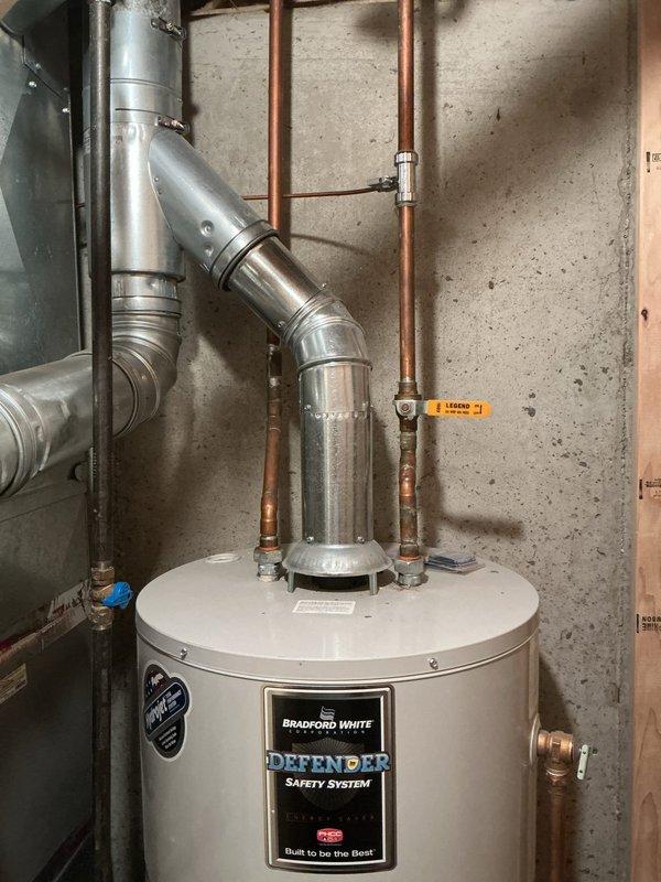 Installed a 40-gallon Bradford White Defender Safety System tanked water heater in residential basement utility area. Reconnected all copper supply and discharge piping, installed appropriate shut-off valves with blue-handled controls, and secured metallic flue vent ductwork to ensure proper exhaust ventilation. Completed gas line connection using flexible yellow connector, verified all connections for proper operation and code compliance.
