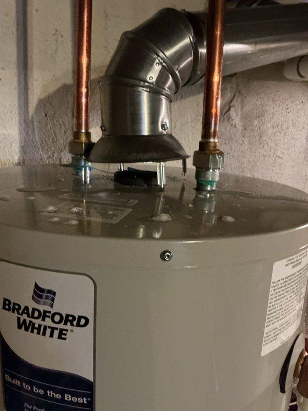 Responded to callback for water heater leak following previous day's installation of furnace and Bradford White water heater. Upon arrival, found active leak at inlet fixture connection entering wall, resulting in standing water around unit and no hot water availability. Inspected installation, verified water heater level and plumbing connections, tightened fixture connection at wall penetration point, and resolved leak. Confirmed proper operation and hot water restoration before departure.