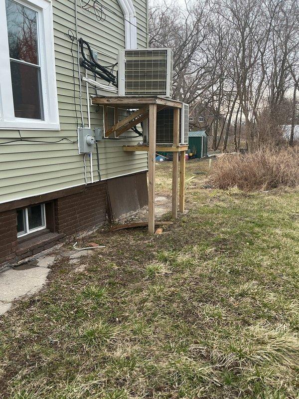 Responded to service call for dual heat pump system where one of two Pioneer units was not operating. Performed diagnostic evaluation on non-functioning 3-year-old unit mounted on exterior wooden platform while confirming newer unit remained operational. Completed troubleshooting procedures and system assessment, with both outdoor condensers photographed for documentation purposes.