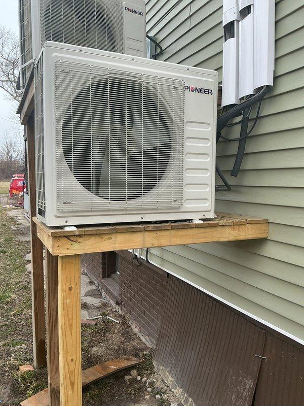 Responded to service call for dual heat pump system where one of two Pioneer units was not operating. Performed diagnostic evaluation on non-functioning 3-year-old unit mounted on exterior wooden platform while confirming newer unit remained operational. Completed troubleshooting procedures and system assessment, with both outdoor condensers photographed for documentation purposes.