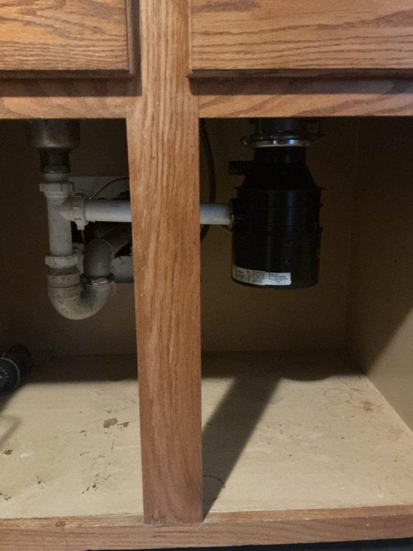 Responded to non-functional garbage disposal in first-floor kitchen sink of 1950s-era home. Upon inspection, found existing black garbage disposal unit mounted under sink with standard drain configuration and P-trap assembly. Assessed unit for electrical connectivity, mechanical jamming, and reset functionality. Disposal showed signs of age and wear consistent with original installation timeline. Restored unit to working condition through troubleshooting and repair procedures. Verified proper drainage, mounting security, and operational performance before completion.