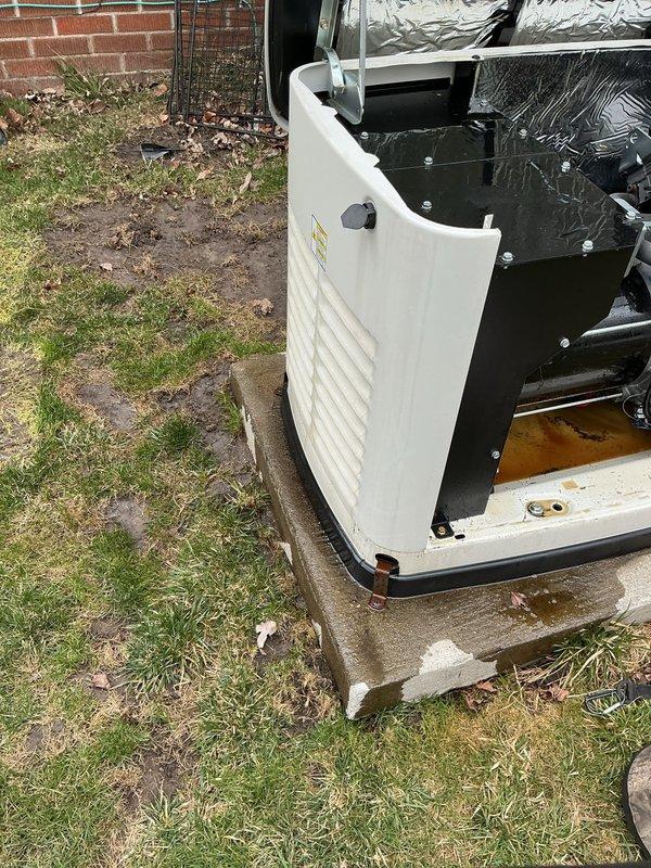 Responded to no-start condition on 14kW Generac generator following recent power outage. Upon arrival, performed visual inspection and found unit with access panel removed, exposing internal components. Observed moisture accumulation in base pan with visible brown liquid pooling, indicating potential drainage issue affecting system operation. Identified orange condensate pump with connected wiring and tubing in lower compartment. Inspected refrigerant lines, insulated piping, and electrical connections for damage or disconnection that could prevent startup. Checked internal housing components and mounting hardware for proper installation. Documented unit condition and component configuration with photographs for service records. Unit positioned on concrete pad showing normal weathering, with all external panels accessible for maintenance procedures.