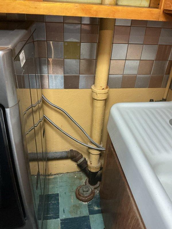 Responded to kitchen sink backup complaint and performed diagnostic inspection of drainage system. Upon arrival, inspected under-sink plumbing configuration and identified issues with drain assembly and trap connections. Examined the existing black trap pipe, white PVC drain lines, and associated fittings for proper installation, blockages, and potential points of failure. Assessed water supply lines and flexible connections for any contributing factors to the drainage problem. Cleared blockage from kitchen sink drain and verified proper water flow through the system, restoring full drainage functionality.