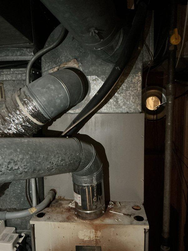 Completed furnace replacement estimate for city rental certification on aging heating system located in basement. Unit over 10 years old barely passed inspection requirements and was deemed safe to operate but nearing end of service life. Comprehensive assessment included evaluation of existing ductwork infrastructure with insulated metal ducts and support systems, inspection of humidifier operation, thermostat functionality, and hot water tank condition. Documented current equipment condition showing age-related wear, dust accumulation, and surface discoloration on cabinet housing and duct connections. Evaluated rigid and flexible ductwork connections, assessed insulation integrity throughout system, and verified proper support bracket installation. Provided replacement recommendations and specifications to bring system up to current efficiency standards and ensure continued safe operation for rental property compliance.