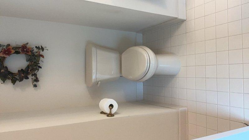 Responded to a leaking toilet tank on the second floor that had persisted for three days following a previous valve replacement attempt. Upon inspection, diagnosed the issue and performed necessary repairs to resolve the leak. Documented the completed work with photos showing the properly functioning toilet in the bathroom with white tile walls and flooring.