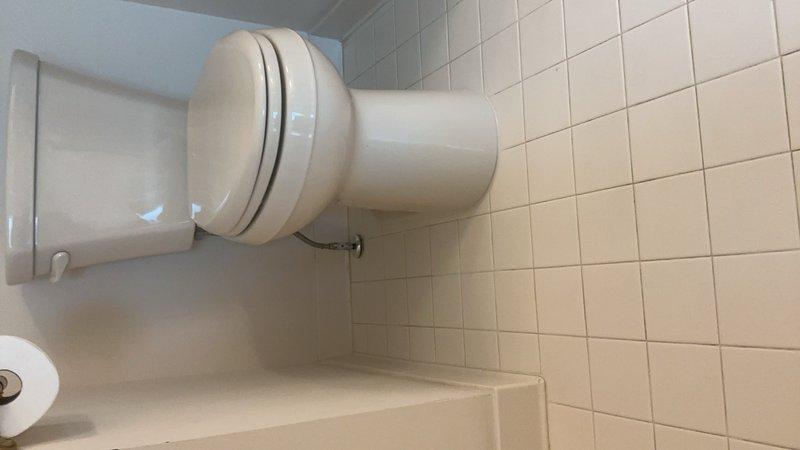 Responded to a leaking toilet tank on the second floor that had persisted for three days following a previous valve replacement attempt. Upon inspection, diagnosed the issue and performed necessary repairs to resolve the leak. Documented the completed work with photos showing the properly functioning toilet in the bathroom with white tile walls and flooring.