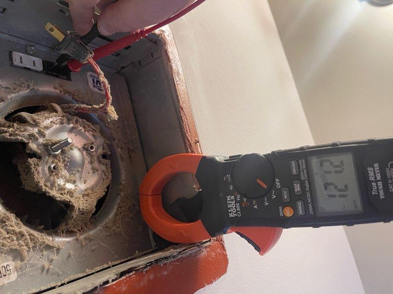 Responded to electrical service call for non-functioning bathroom light and multiple outlets inoperative following wind storm and power outage. Performed diagnostic testing using digital clamp meter to measure current and identify circuit issues. Discovered severe corrosion and deterioration on electrical outlet components and junction boxes, with heavy rust accumulation compromising connections. Inspected electrical panel revealing significant debris buildup, dust, and fibrous insulation material obstructing access points and surrounding electrical components. Addressed circuit overload conditions that previously caused breaker trips when multiple outlets were used simultaneously. Troubleshot and restored power to affected circuits throughout the residence.