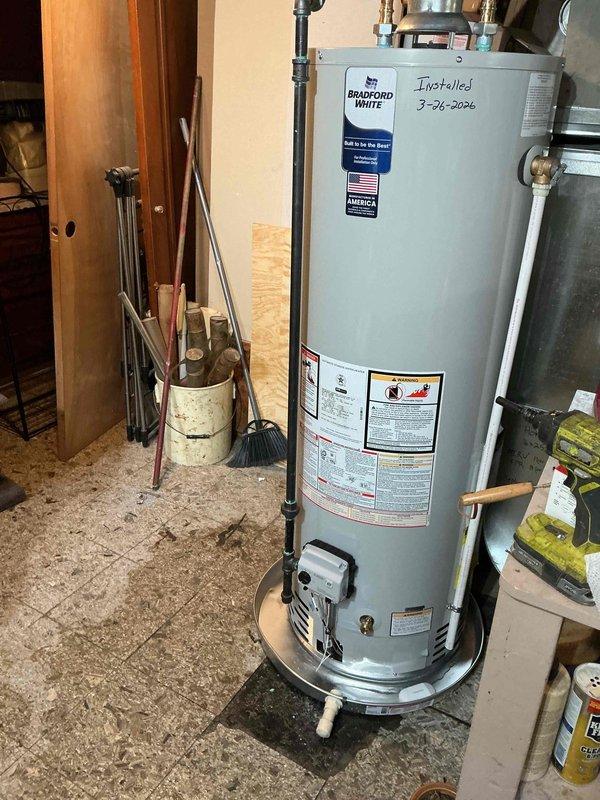 Installed a 40-gallon Bradford White tanked water heater in utility area with all necessary plumbing connections including copper supply lines and fittings. Unit was properly positioned on a drain pan with alarm system for leak detection and secured according to manufacturer specifications and local code requirements.