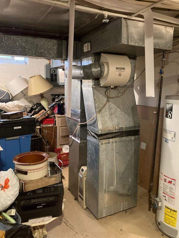 Conducted comprehensive assessment of 20-year-old residential HVAC system for full replacement estimate. Evaluated exterior air conditioning condenser unit mounted on concrete pad with electrical disconnect, noting age-related wear and operational status. Inspected basement furnace/air handler with galvanized steel cabinet, associated ductwork, humidifier components, and copper refrigerant lines to determine complete system replacement specifications and provide detailed quote for new equipment installation.