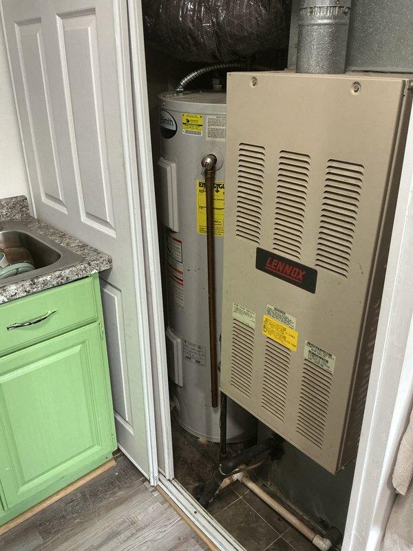 Responded to complaint of burning smell originating from tanked water heater in first-floor kitchen utility closet. Upon arrival, conducted thorough inspection of water heater unit and surrounding mechanical equipment including adjacent furnace system. Examined water heater exterior, connections, venting system, and associated copper piping for signs of overheating, electrical issues, or mechanical failure. Inspected flue pipe configuration and draft hood assembly for proper venting and potential backdraft conditions. Verified gas connections, burner assembly access, and surrounding insulation materials for heat damage or deterioration. Documented equipment condition with photographs showing water heater placement in compact closet space alongside HVAC equipment. No immediate safety hazards identified requiring emergency shutdown during inspection period.