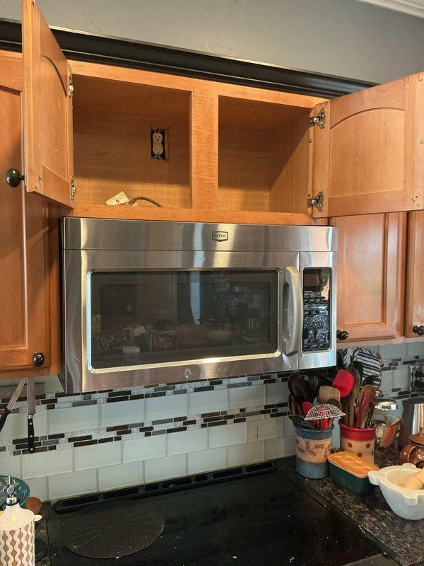 Performed diagnostic evaluation of over-the-range microwave ventilation system in kitchen. Found unit operating in recirculation mode with exhaust air venting back into space behind microwave rather than being properly ducted to building exterior through available exterior wall. Assessed existing installation configuration, cabinet arrangement, and potential exterior venting pathway to provide recommendations for converting recirculating system to proper exterior exhaust ventilation.