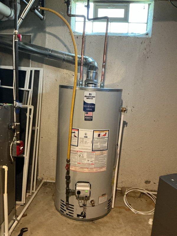Completed installation and reconnection of a 50-gallon Bradford White tanked water heater in residential basement utility room. Connected copper supply lines, yellow flexible gas line, pressure relief valve, and all necessary piping to bring unit into full operation. All connections were properly secured and tested to ensure safe and efficient operation of the new water heating system.